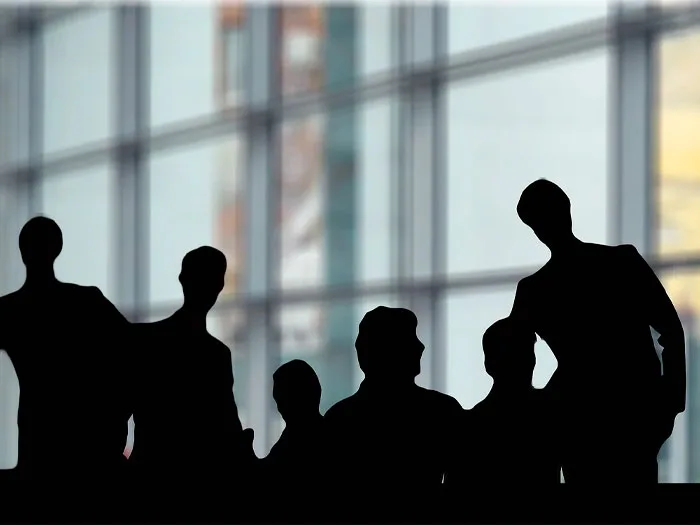 Silhouettes de professionnels collaborant en groupe, symbolisant la coopétition et le partenariat stratégique dans un environnement d'affaires moderne.
